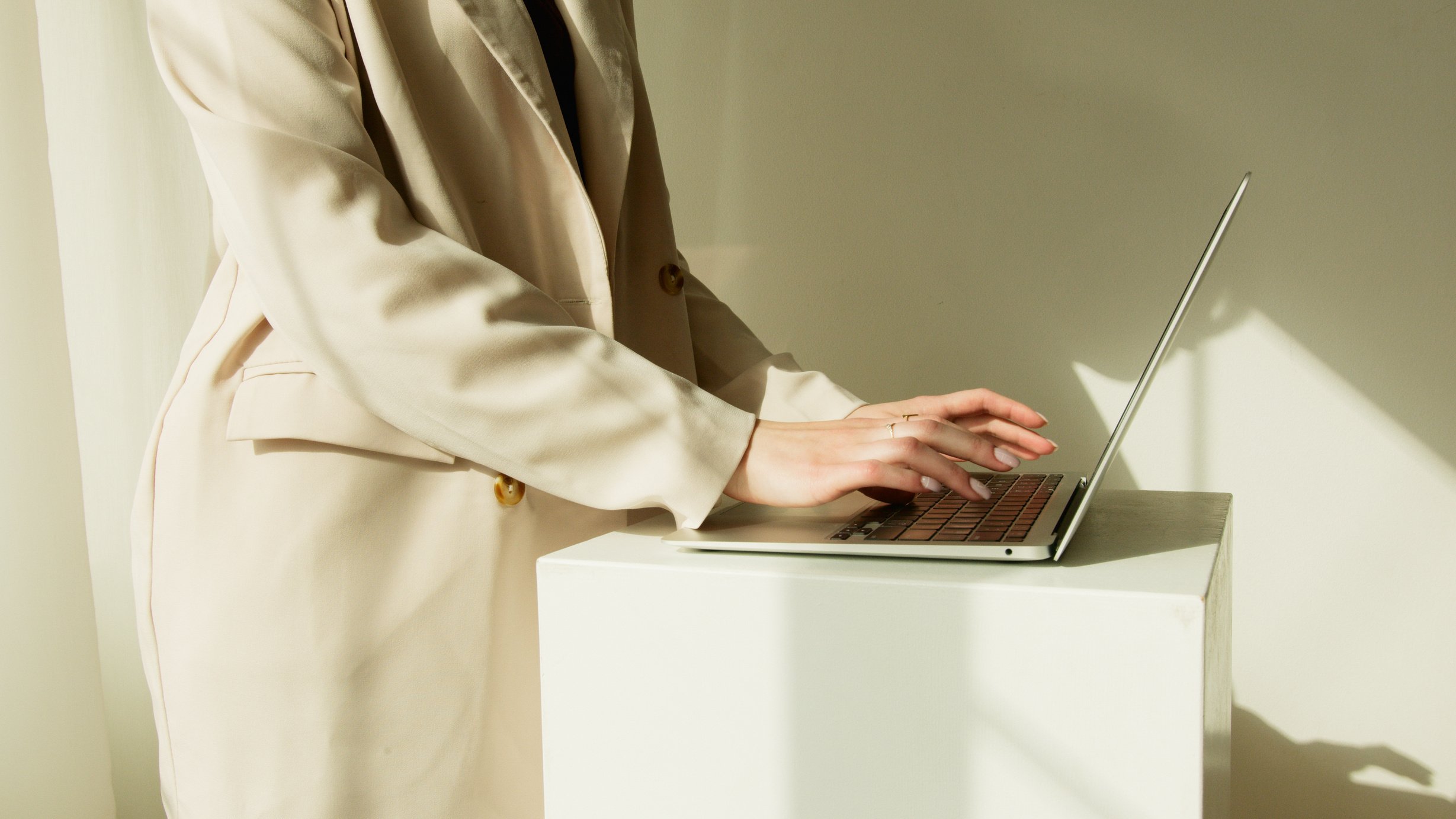 Person in Beige Coat Typing on Her Laptop
